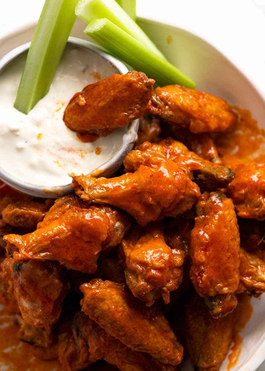 Pile of buffalo wings with blue cheese dip and celery sticks