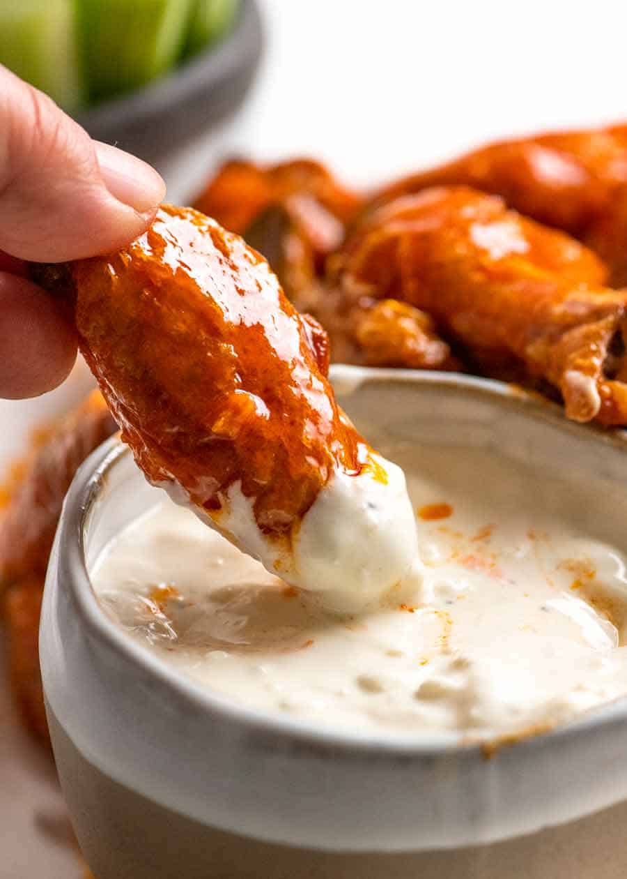 Close up dipping buffalo wing into blue cheese dip