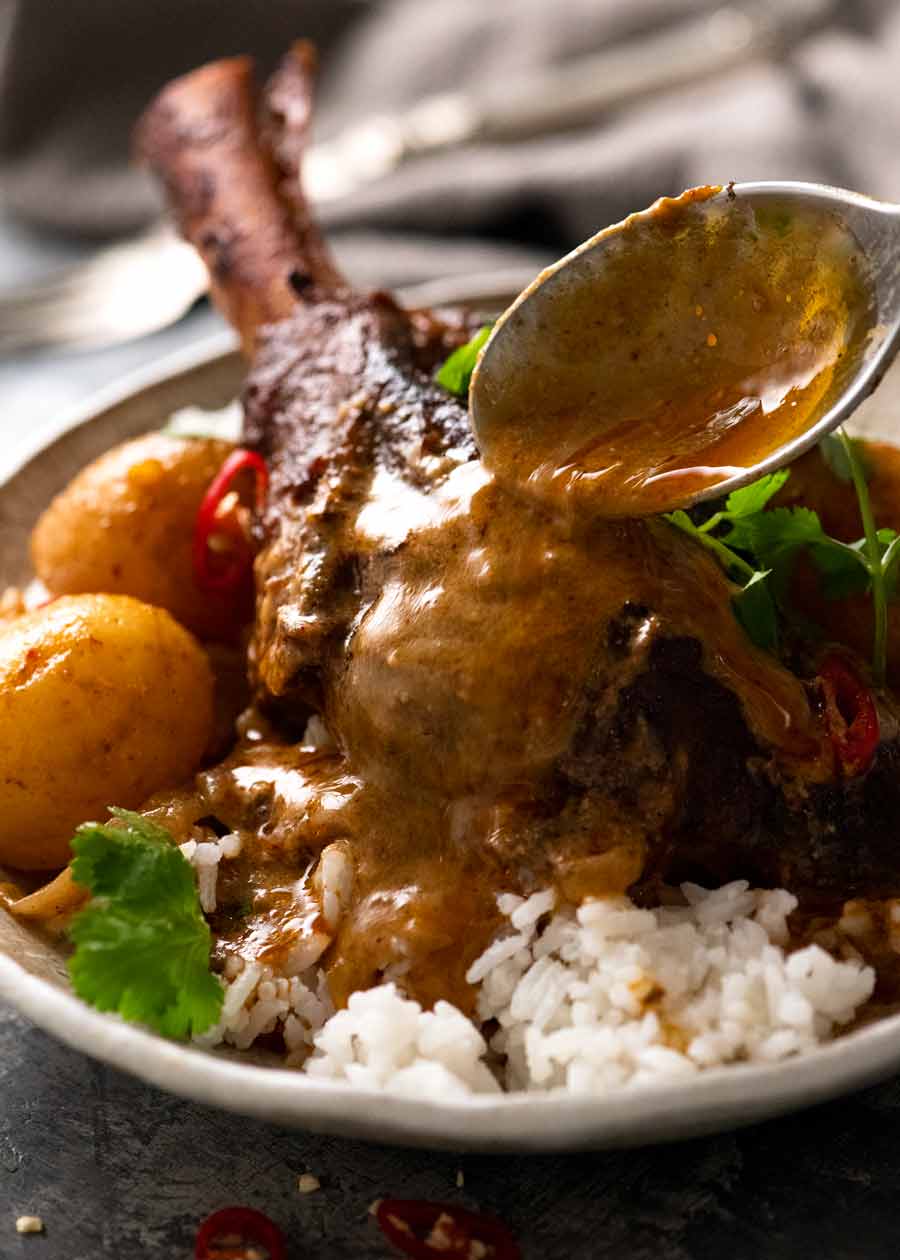Pouring Massaman Curry over slow cooked lamb shanks