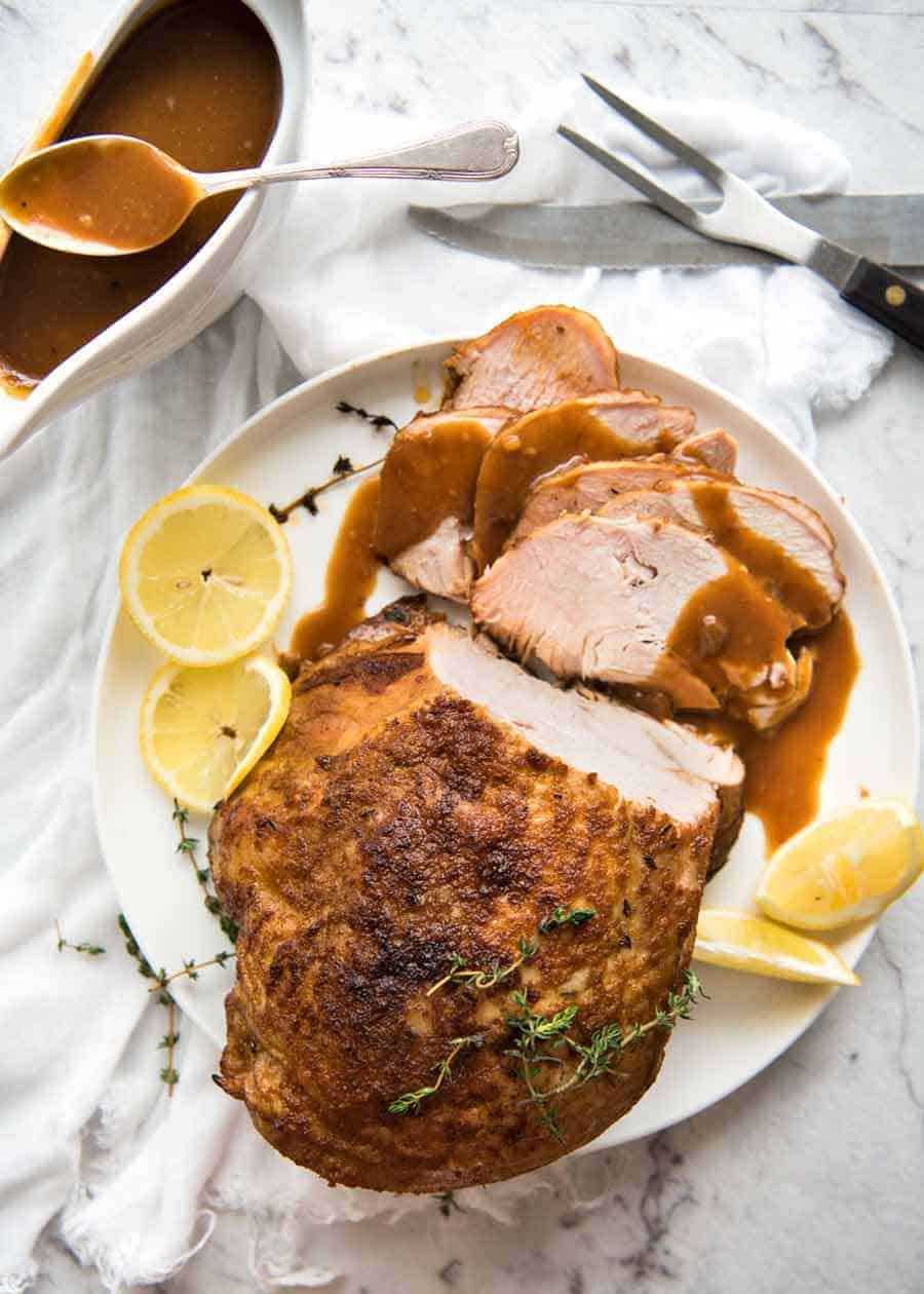 Overhead photo of Slow Cooker Turkey Breast on a white plate, with gravy on the side
