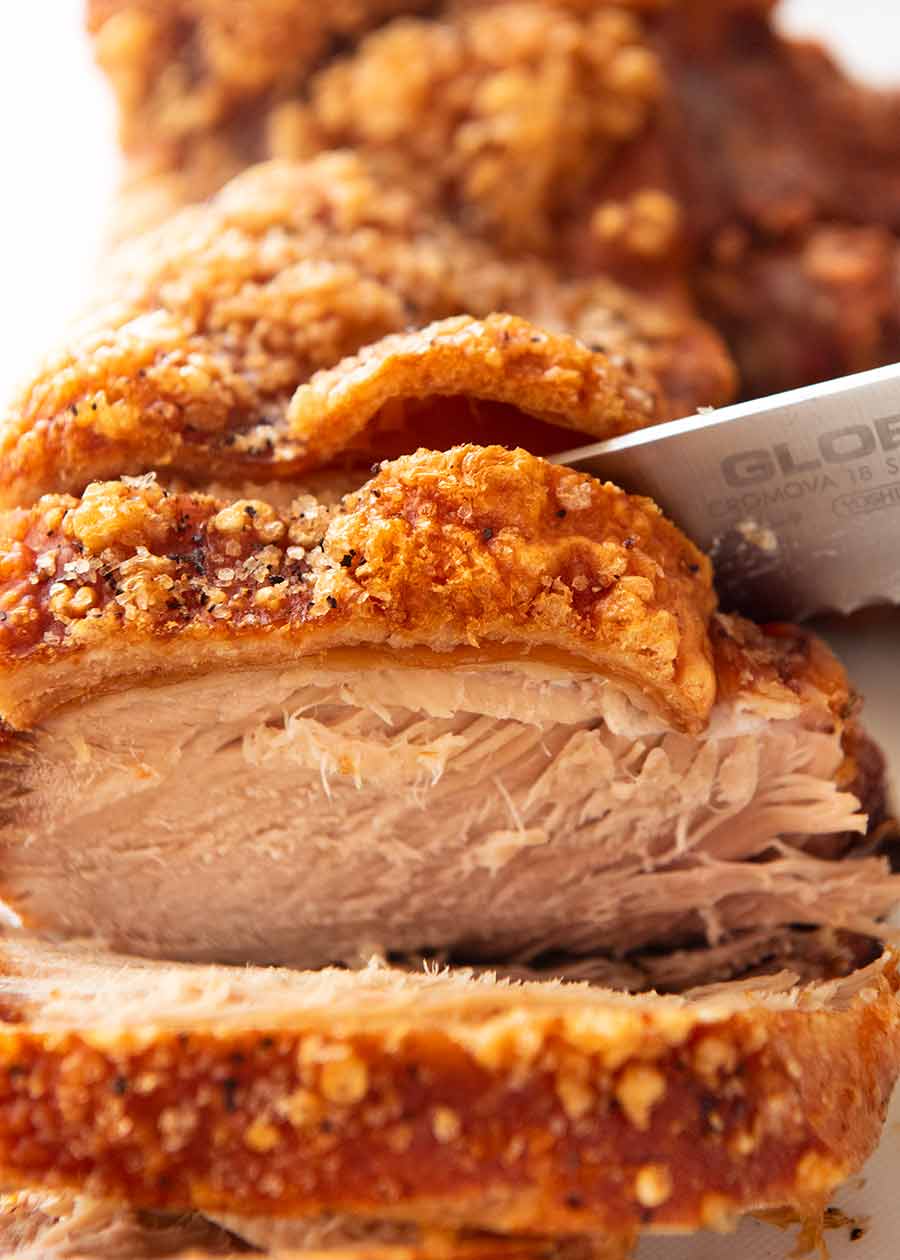 Close up slicing perfect pork roast with crispy crackling